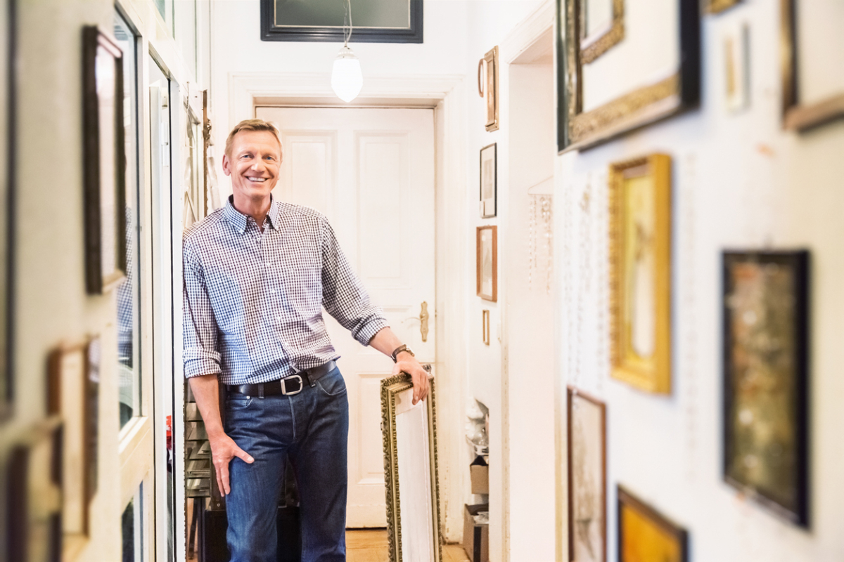 A man in a hallway full of art.
