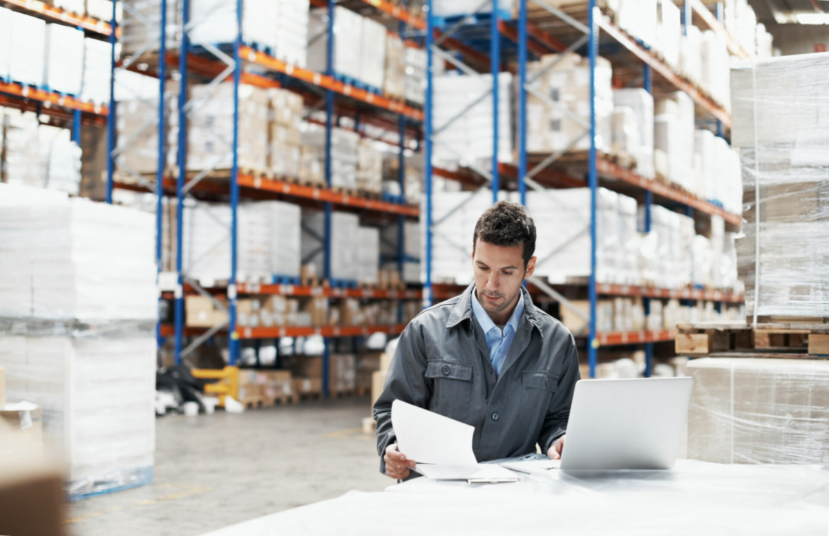 A man in a warehouse calculates inventory turnover ratio.