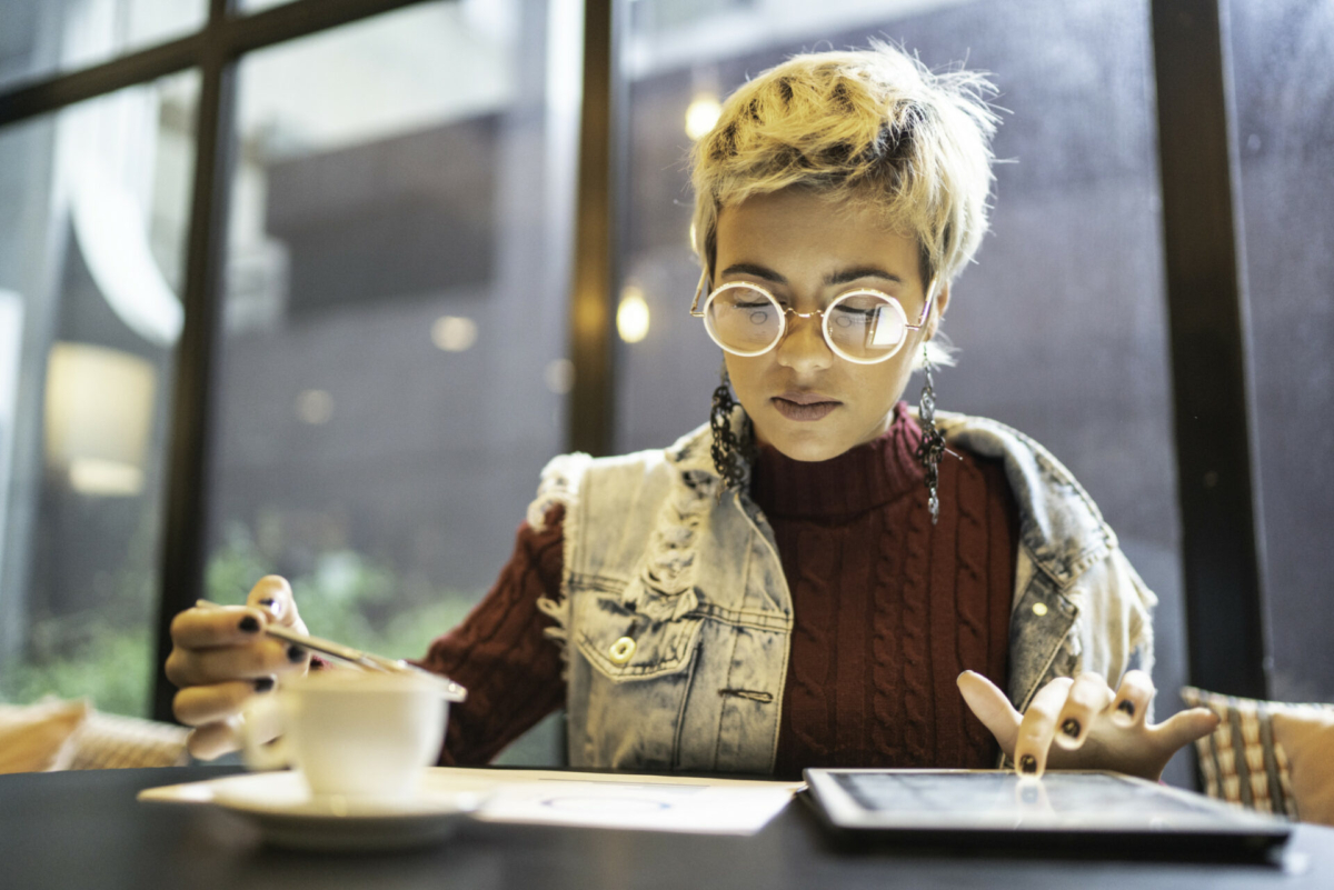 A woman reviews business reports on paper and on a tablet.