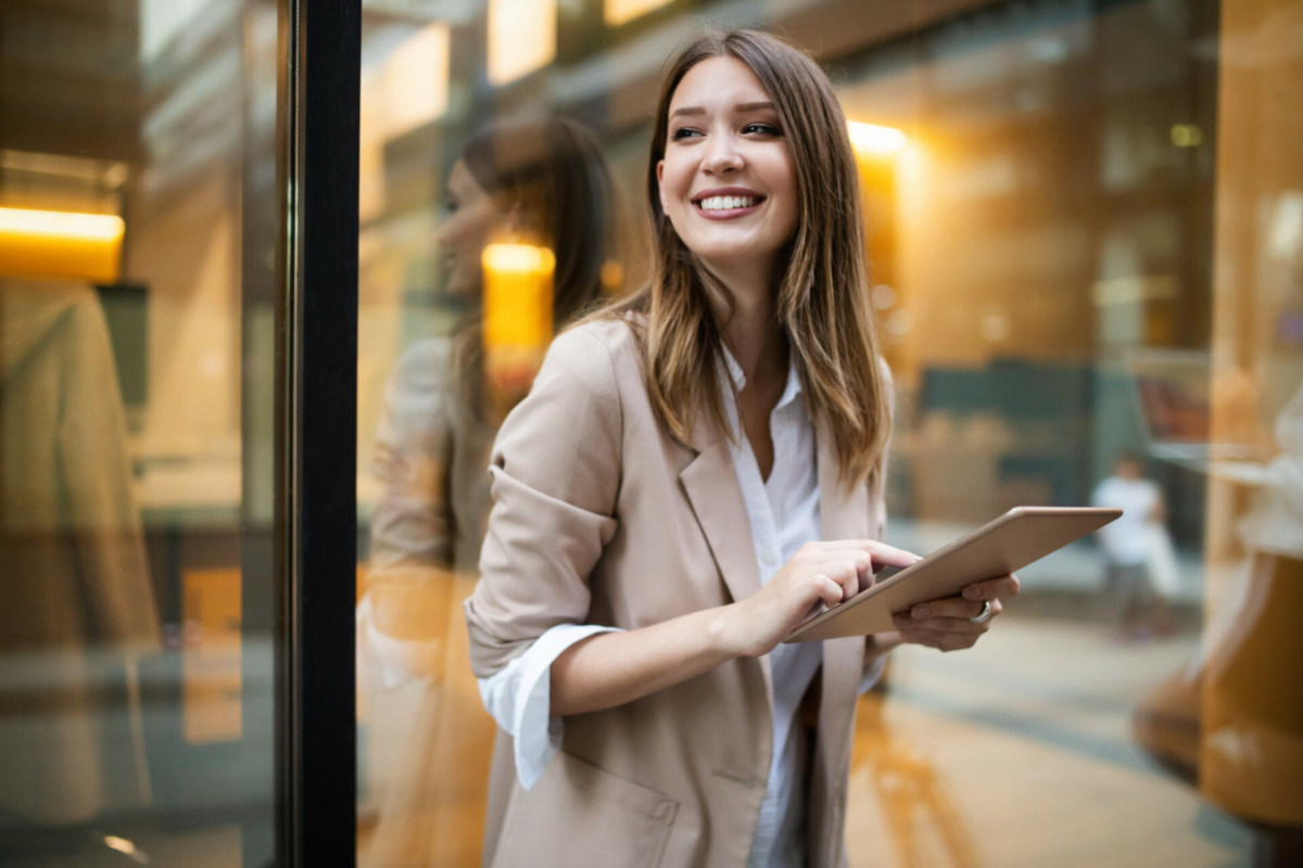 A woman smiles while using a tablet to review business information.