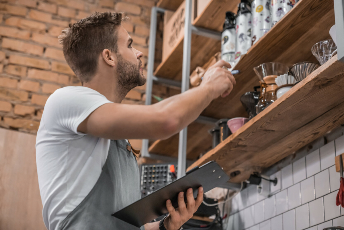 A coffee shop employee takes inventory using a tablet.