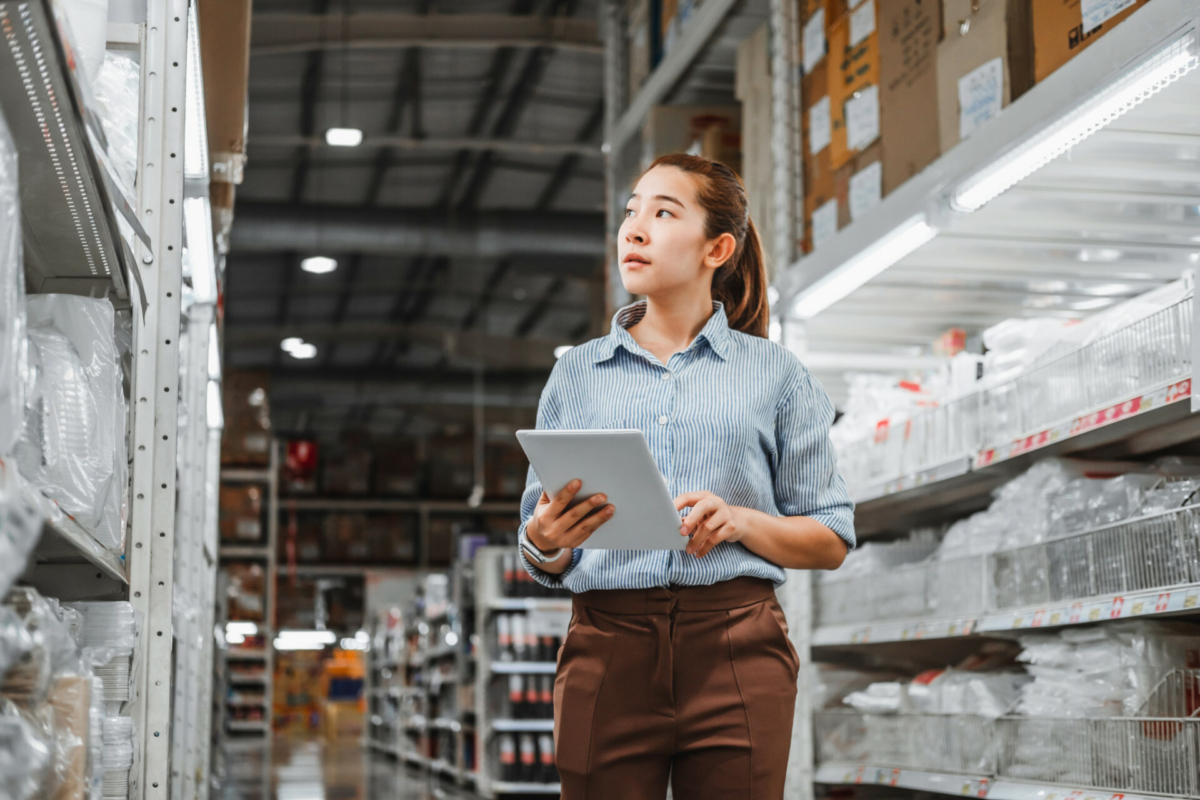 what is inventory management - A woman inventories a stockroom using a tablet.