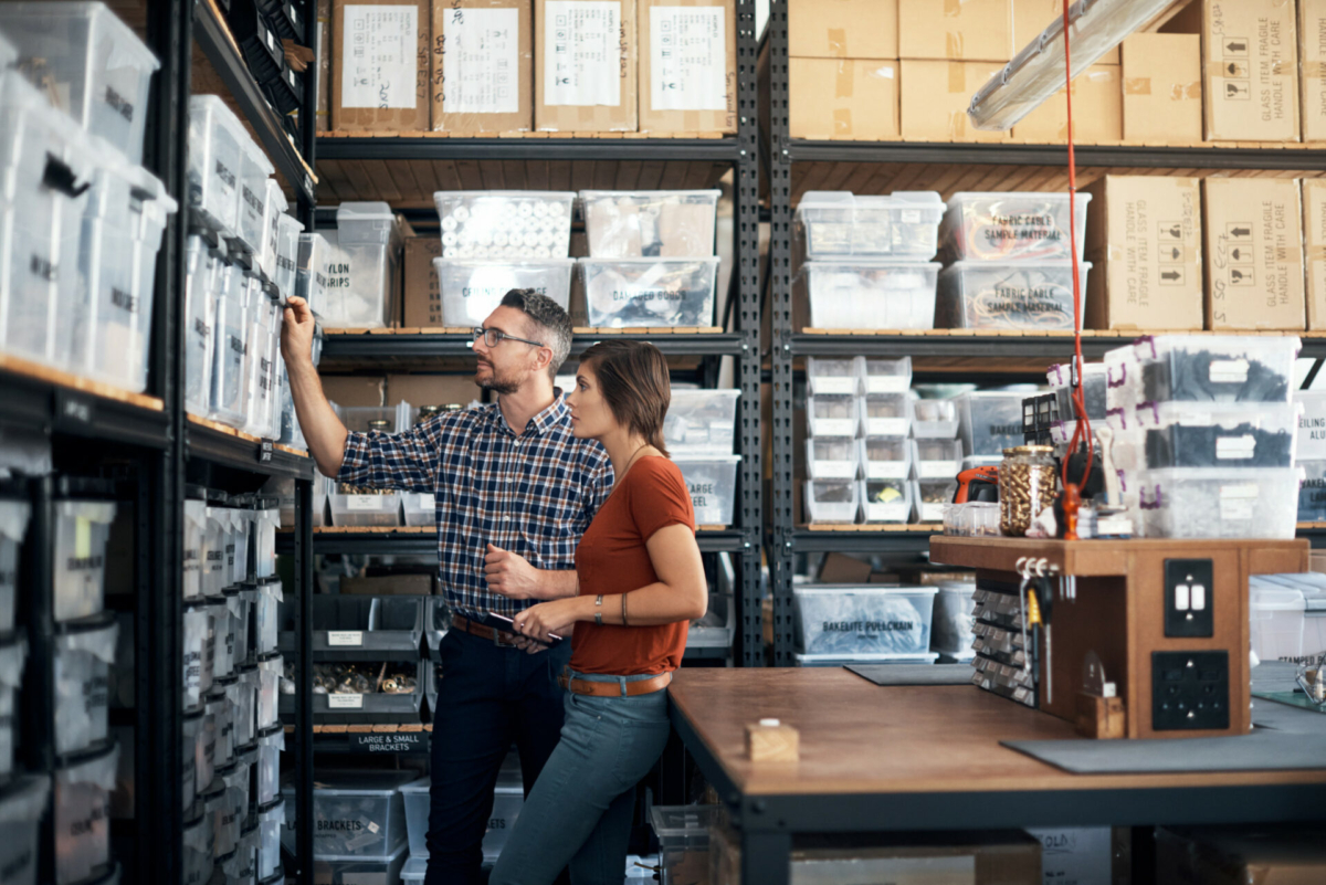 A man and a woman look through stocked shelves.