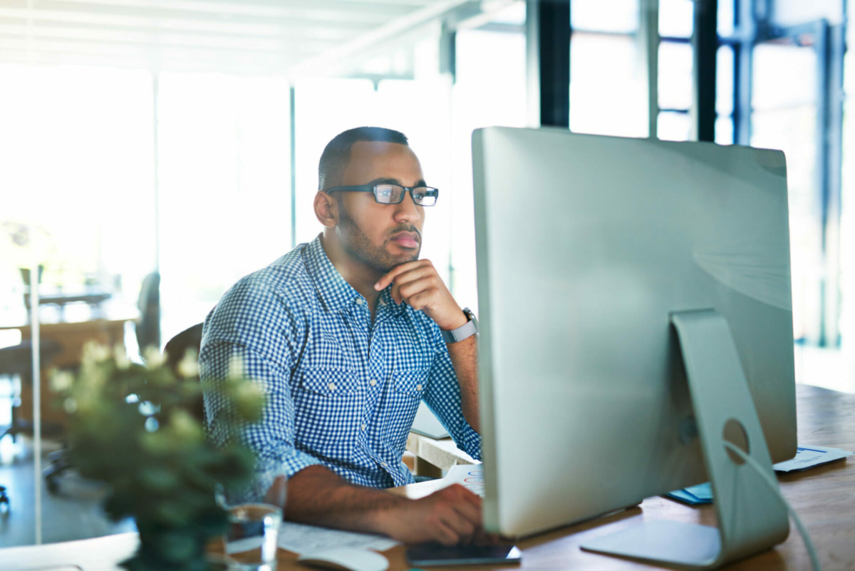 A man in a work attire looks at his computer.