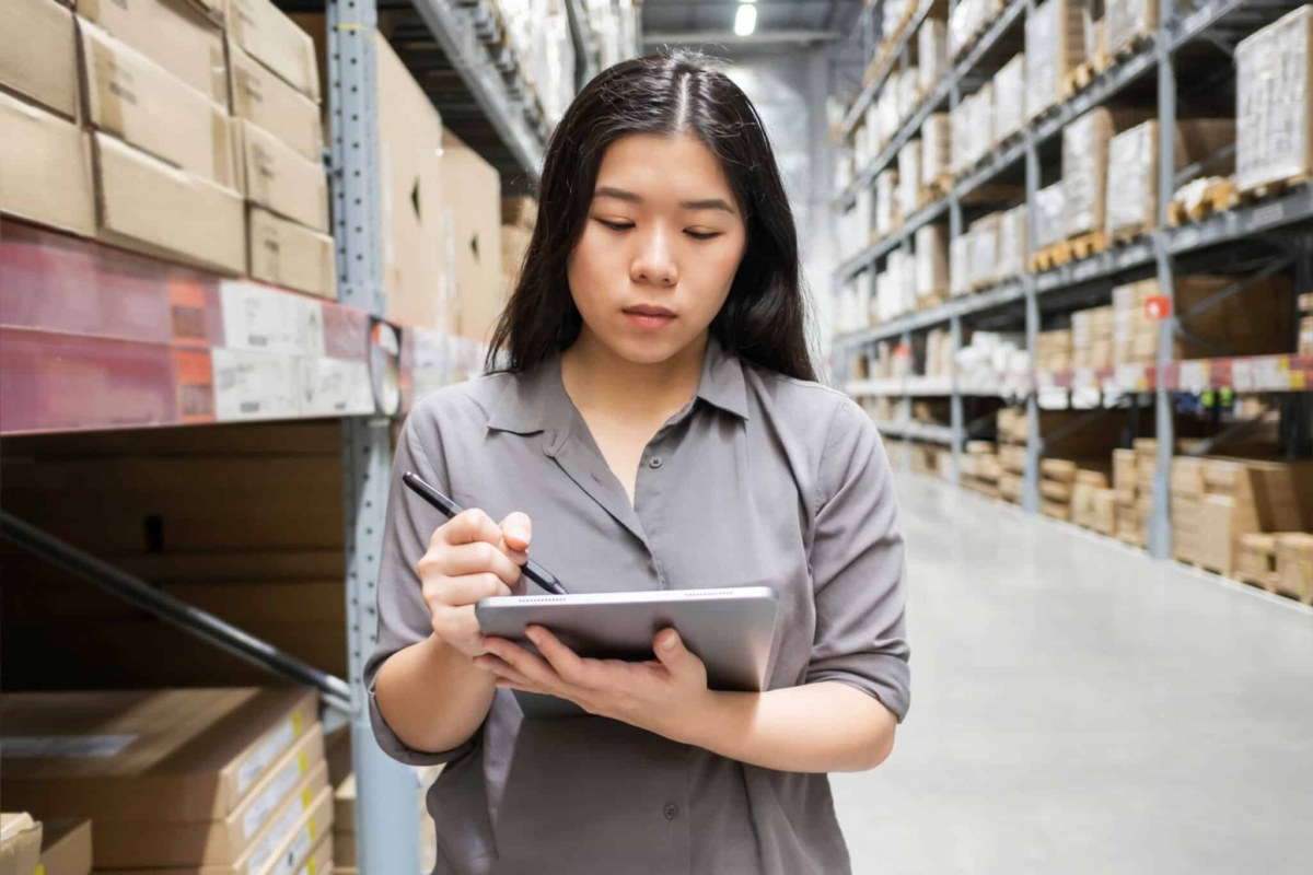 A woman conducts inventory cycle counts in a warehouse.
