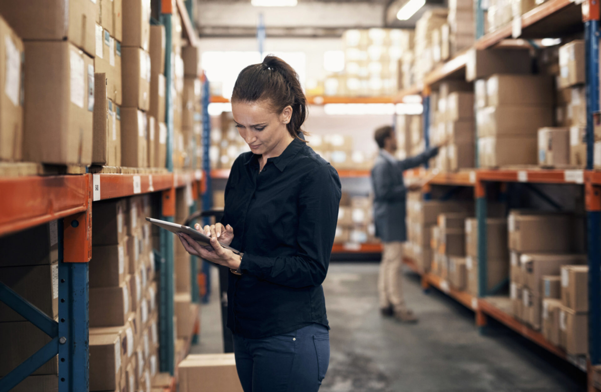 Woman in warehouse calculating anticipation inventory