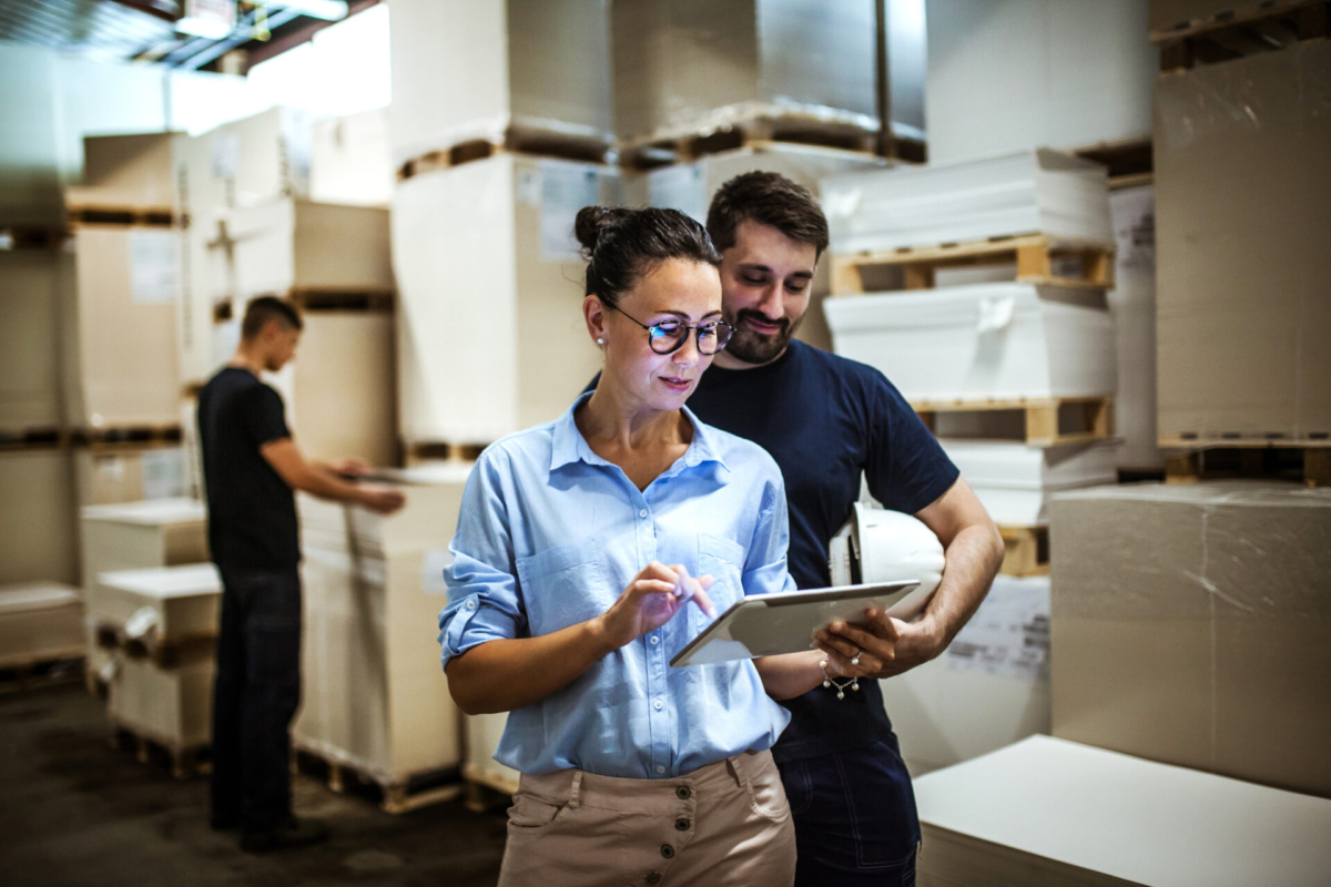 Two employees look at a Sortly purchase order on a tablet