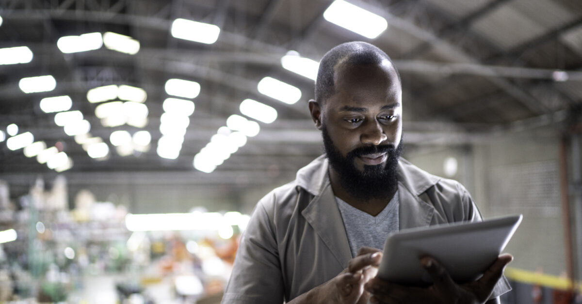 A man in a warehouse uses software for optimized inventory control.