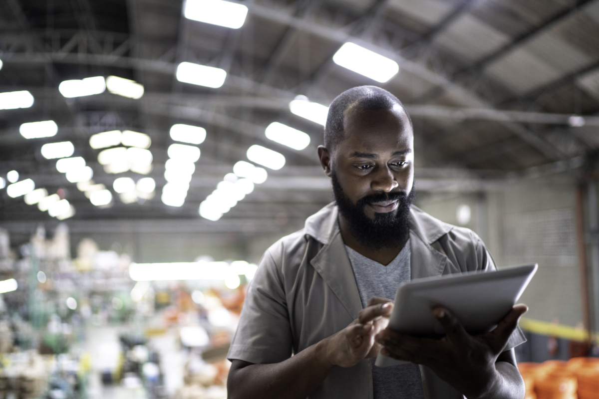 A man in a warehouse uses software for optimized inventory control.