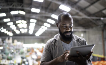 A man in a warehouse uses software for optimized inventory control.