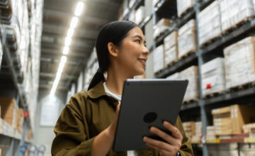 A woman uses warehouse management software on a tablet.